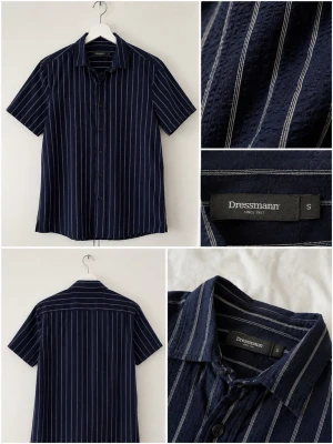 Mörkblå randig skjorta Dressmann - Kortärmad skjorta från Dressmann i mörkblått med vita vertikala ränder. Klassisk krage och knäppning framtill. Perfekt för en avslappnad men ändå stilren look. Tillverkad i mjukt bomullsmaterial.
