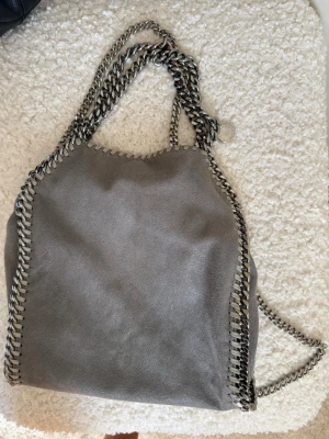 Grå Stella McCartney handväska - Mellanstorleken. Har tyvärr två fläckar på baksidan som syns på andra bilden. De är små och syns inte när man har på sig väskan.