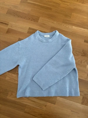 Ljusblå stickad tröja Gina Tricot - Mysig ljusblå stickad tröja från Gina Tricot i ullblandning. Tröjan har rund halsringning, ribbade muddar och avslut. Perfekt för kalla dagar och enkel att matcha till olika outfits.