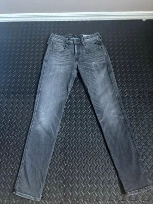 Grå slim fit jeans med slitningar - Snygga grå jeans i slim fit-modell med diskreta slitningar framtill. Jeansen har klassisk femficksdesign, normal midja och dragkedjegylf. Materialet är troligtvis bomull med stretch för extra komfort.