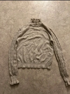 Beige stickad tröja med volangkrage - Supersöt beige stickad tröja med volangkrage och volang längst ner på ärmarna. 