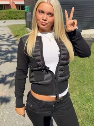 Moncler Cardigan - Snygg svart cardigan från Moncler med quiltad front och dragkedja. Västen har en klassisk passform, två fickor framtill och Moncler-logga på ärmen. Perfekt att slänga över en hoodie eller långärmad tröja för en cool look.
