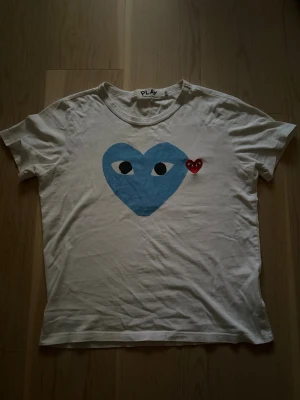 T-shirt från commes des garçons  - Säljer denna snygga vita T-shirt från commes des garçons med det kända blåa hjärtat. Den sitter bättre på xs därav storleken. På varan står det dock s. 