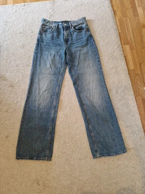Blå raka jeans från Stradivarius - Säljer ett par klassiska blå jeans från Stradivarius i storlek 36. Jeansen har rak passform, hög midja och fem fickor. Materialet är denim i 100% bomull med snygg tvättad look. Perfekta vardags jeans.