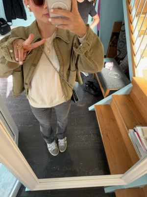 Zara grön jacka - Säljer en Zara Grön Jacka med avslappnad passform och stora knappar framtill. Jackan har klassisk krage och långa ärmar, perfekt att slänga över en t-shirt för en cool och enkel look.