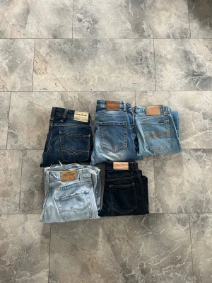 Fem par klassiska blå jeans - Säljer fem par jeans i olika blå nyanser, från ljusblått till mörkblått. Alla har raka ben och klassisk femficksdesign med läderpatch bak i midjan. Perfekta för dig som gillar tidlös denimstil och vill ha flera alternativ i garderoben Ge bud till de OCH KÖP INTE ANNONSEN 