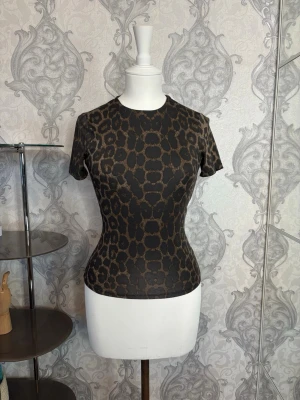 Leopardmönstrad topp - Snygg leopardmönstrad topp med korta ärmar och rund hals. Tunn och stretchig modell som sitter tight och ger en cool look. Perfekt att styla med jeans eller kjol för en trendig outfit.