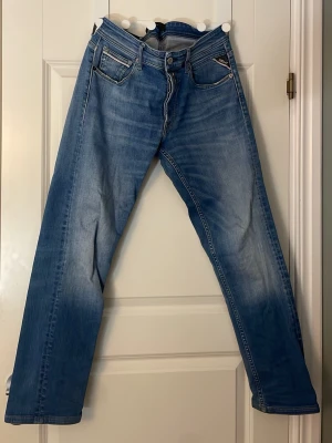 Replay jeans - Snygga blå jeans från Replay i modellen straight fit. Jeansen har klassisk femficksdesign, normalhög midja och raka ben. Tillverkade i slitstarkt denim med ljus tvätt och subtila slitningar för en avslappnad look.