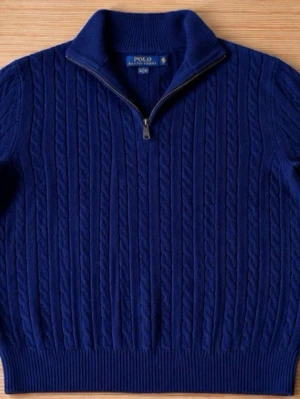 Blå kabelstickad tröja Polo Ralph Lauren - Mörkblå kabelstickad tröja från Polo Ralph Lauren. Perfekt tröja nu till höst och vinter. Ai genererat pga dåligt ljus men nu kan bara skriva om ni vill ha mer bilder.