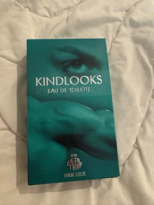 Kindlooks Eau de Toilette parfym - Kindlooks Eau de Toilette är en parfym i en stilren, turkosgrön förpackning med ett konstnärligt öga på framsidan. Förpackningen är rektangulär och har silverfärgad text. Volymen är 100 ml (3.3 FL.OZ). Säljs för 180kr