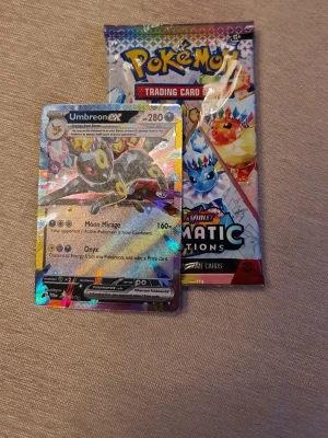 Pokémon kort Umbreon - Säljer ett Pokémon trading card med Umbreon ex och ett boosterpack från Scarlet & Violet Paldean Fates. Kortet är holografiskt med färgglada detaljer och motiv av Umbreon. Perfekt för samlare eller dig som vill utöka din kortsamling.