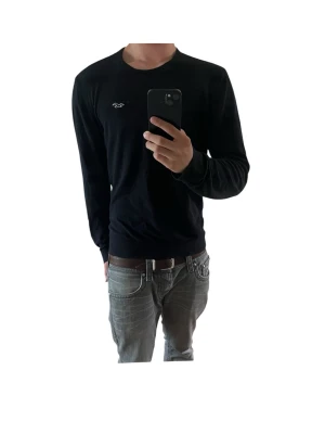Svart stickad tröja från Hollister - Svart stickad tröja från Hollister med rund halsringning och diskret logga broderad på bröstet. Tröjan har långa ärmar och ribbade muddar vid ärmslut och nederkant. Perfekt för lager på lager och enkel att matcha med jeans. Storlek L slim fit men passar mer som M Modellen i bilden är 180cm 69kg och bär vanligtvis kläder i storlek M
