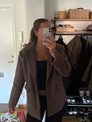 Brun oversized kavaj med fickor - Brun kavaj/jacka i oversized modell med bred krage och två fickor framtill. Materialet är mjukt och har en lätt fluffig struktur som ger en avslappnad vibe. 