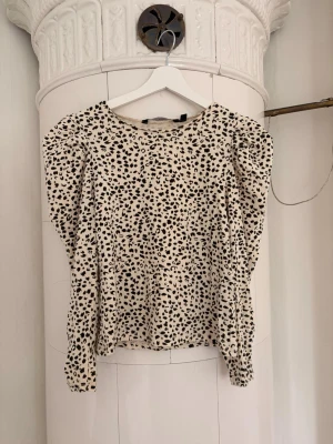 Leopardmönstrad blus från KappAhl - Trendig blus från KappAhl i beige med svart leopardmönster. Blusen har puffiga axlar och halvlånga ärmar med smalare avslut. Tillverkad i ett mjukt, stretchigt material som sitter snyggt på kroppen. Perfekt för dig som vill sticka ut lite extra.