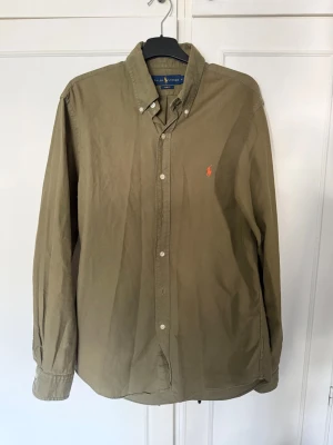 Skjorta Ralph Lauren - Klassisk olivgrön skjorta från Ralph Lauren med slim fit passform. Inga defekter eller liknade och är i mycket bra skick. Perfekt till ett par jeans, chinos eller under en stickad tröja
