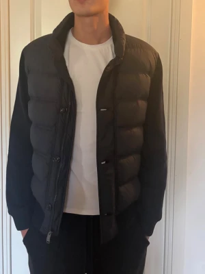 mörk blå jacka - Snygg mörk blå  jacka med hög krage och quiltad design. jackan  har dragkedja och knappar framtill samt diskret logomärke på vänster axel. Perfekt för lager-på-lager och ger en clean look till din outfit. Vid snabb affär så kan jag tänka mig att gå ner i pris 