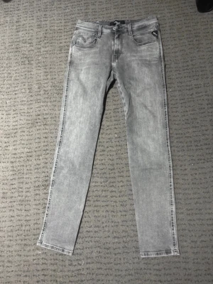 Grå replay slim fit jeans - Gråa replay jeans. Jeansen har en tvättad look och detaljerade sömmar på bakfickorna. Perfekta för dig som gillar en stilren och modern vibe.