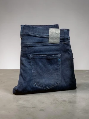 Mörkblå slim fit jeans från Replay - Snygga mörkblå jeans från Replay i slim fit-modell. Klassisk femficksdesign med diskreta detaljer och metallknapp. Jeansen har en stilren look och är tillverkade i stretchigt denimtyg för extra komfort. Tagen där storleken syns gick sönder i tvättmaskinen men den passar ungefär de som när storleken xs-s 