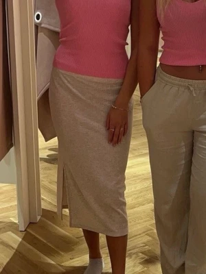 Beige ribbad midikjol med slits - Säljer en beige ribbad midikjol med slits på sidan. Kjolen har en kroppsnära passform och är gjord i ett stretchigt, mjukt material 