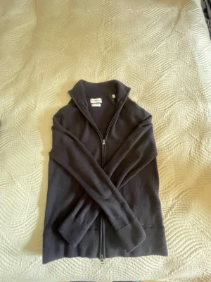Svart helzip These Glory Days -  Svart helzip These Glory Days med hög krage och hel dragkedja framtill. Långärmad modell som passar perfekt för kyligare dagar. Enkel och stilren design utan synliga loggor eller mönster.