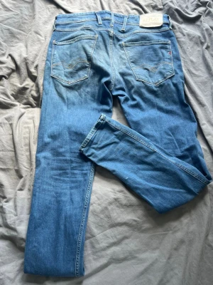 Ljusblå raka jeans från Replay - Säljer ett par ljusblå jeans från Replay med raka ben och klassisk femficksmodell. Jeansen har snygga slitningar framtill och bakfickor med diskreta detaljer. Perfekta för en avslappnad och trendig look. Modellen är ambass slim fit. Storlek är w32 och l 32 pris kan diskuteras vid snabb affär