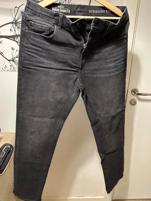 Svarta straight fit jeans från Next - Säljer ett par svarta straight fit jeans från Next Denim Goods Co. Jeansen har klassisk femficksdesign, dragkedjegylf och är tillverkade i ett mjukt denimtyg. Perfekta för dig som gillar en enkel och stilren look.