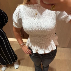 Vit smockad blus med puffärm - Supersöt vit blus med smockad överdel och volang nertill. Puffiga korta ärmar. Säljer pga inte kommer till användning. Använd endast en gång🙌❤️(passar både xs/s)