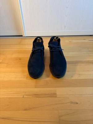 Mörkblå mockakängor med snörning - Snygga kängor i mörkblå mocka med klassisk snörning och låg klack. Skorna har en stilren och enkel design med rundad tå och diskreta sömmar. Perfekta för dig som gillar en clean och modern look. Skoblock ingår inte!
