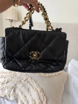Real leather bag  - Snygg svart handväska. Väskan har en chunky kedjerem i guld och svart, samt ett rymligt innerfack. Perfekt accessoar för dig som gillar lyxig och tidlös design.