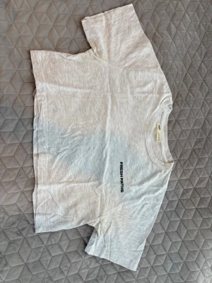 Ljusgrå croppad t-shirt Fresh Paths - Säljer en ljusgrå croppad t-shirt med svart texten 'FRESH PATHS' på bröstet. T-shirten har rund halsringning och korta ärmar. Tillverkad i mjuk bomull, perfekt för en avslappnad och trendig stil.