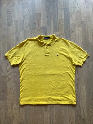 Polo Ralph Lauren - piké - gul, XL - Mycket bra skick. Inga tecken på användning Piké från Polo Ralph Lauren, storlek XL, gul Klassisk krage med två knappar, mörkblå logga vänster bröst Bröstvidd: 63 cm Längd: 73 cm Inga defekter