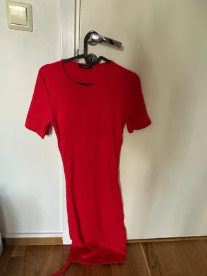 Röd kortärmad klänning Trendyol - En enkel och snygg röd klänning från Trendyol med korta ärmar och rund halsringning. Klänningen har en rak passform och är tillverkad i ett mjukt, ribbat material som ger en bekväm känsla.