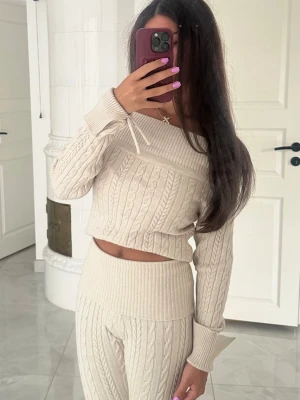 Beige stickat loungewear-set - Mysigt loungewear-set ifrån Gina Tricot i beige med kabelstickat mönster. Tröjan har off-shoulder design, långa ärmar och bred mudd vid ärmslut. Byxorna är höga i midjan och har samma stickade struktur. Perfekt för chill dagar hemma. Byxorna är i storlek XXS medan toppen är i XS☺️💕