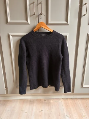 Mörkgrå stickad tröja från Uniqlo - Klassisk mörkgrå stickad tröja från Uniqlo i enkel design. Tröjan har rund halsringning, långa ärmar och ribbstickade muddar vid ärmslut och nederkant. Perfekt basplagg i garderoben och passar till det mesta.