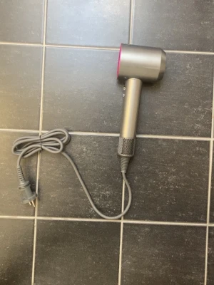 Dyson Supersonic HD08 – Oanvänd – 4 tillbehör - Säljer en Dyson Supersonic HD08 i nyskick. Hårfönen är helt oanvänd, den har endast tagits upp ur förpackningen och rörts.  Den torkar håret snabbt med kraftfullt luftflöde och intelligent värmekontroll som hjälper till att skydda håret från onödiga värmeskador.  Ingår:  * Dyson Supersonic HD08 * 4 originaltillbehör * Strömkabel  Observera: Originalkartongen och kvittot finns tyvärr inte kvar eftersom jag fick den i present. Därför medföljer varken box eller kvitto.  Säljs eftersom jag inte har 