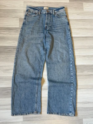 Blå raka jeans - Klassiska blå jeans från Jack & Jones med rak passform och hög midja. Jeansen har fem fickor, bälteshällor och råa kanter vid bensluten för en avslappnad look. Tillverkade i kraftigt denimtyg som ger en tidlös vintagekänsla.