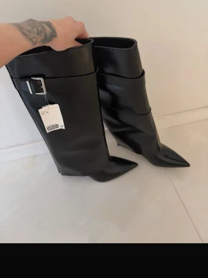Svarta höga boots med spetsig tå - Säljer dessa super snygga bootsen från H&M, aldeig använda i storlek 38. Bandet på första bilden har jag tappat bort. Köptes döe 700kr