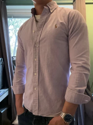 Rosa Ralph lauren skjorta - Snygg skjorta från Ralph lauren som sitter med en perfekt passform🤩.Perfekt skick med fint material. Storlek S, är 177cm på bilden. Då sitter den lite kort. Skicka gärna prisförslag och frågor!😄