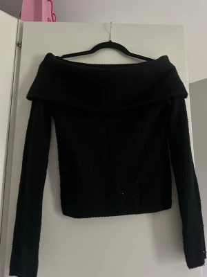 Svart off shoulder stickad tröja - Säljer en svart stickad tröja med off shoulder-design och långa ärmar. Tröjan har en bred krage som vilar över axlarna och är ribbstickad för en snygg och bekväm passform. Perfekt nu till hösten🥰🍁🍂 Tröjan är i storlek S och väldigt lite använd!