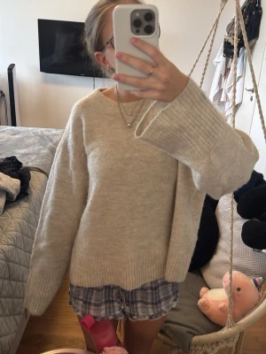 Beige stickad tröja från Gina Tricot - Mysig beige stickad tröja från Gina Tricot med avslappnad passform och breda ribbade muddar vid ärmslut och nederkant. Pris kan diskuteras