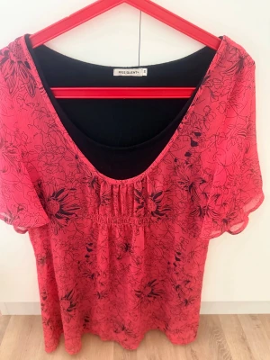 Säljer en fin damblus från Freequent  - 🌺❤️👚✨ Säljer en fin damblus från FREE|QUENT i storlek S 🌸🖤  Den vackra röda färgen med svarta blommor 🌺🌿 ger blusen en feminin och stilfull look 😍✨ Tillverkad i ett tunt och luftigt material 🌬️☀️ Perfekt för varmare dagar 🌼  Underblusen är fastsydd i svart 🖤👕, vilket gör att den sitter snyggt och är bekväm att bära 💃  Mycket fint skick 💎👌  📏 Mått: 📐 Bredd: 94 cm (kan töjas upp till 104 cm) 📏 Längd: 70 cm  Välkommen att köpa 🛍️😊🌷