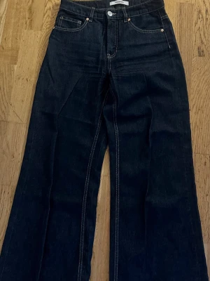 Mörkblåa vida jeans med hög midja - Snygga mörkblå jeans med hög midja och vida ben. Klassisk femficksmodell med kontrastsömmar och raka, långa ben. Perfekta för en trendig och avslappnad look. Tillverkade i denim med tydlig struktur. Nypris : 599kr 