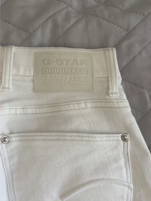 Vita jeans från G-Star RAW - Säljer ett par vita jeans från G-Star RAW Originals. Klassisk femficksmodell med raka ben och snygga detaljer i silver vid fickorna. Tillverkade i kraftig denim som ger en schysst och stilren look. Perfekta för dig som vill sticka ut med ljusa jeans.