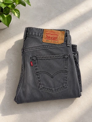 Grå Levi's 501 jeans - Säljer ett par klassiska grå Levi's 501 jeans med raka ben och femficksmodell. Jeansen har den ikoniska läderpatchen bak i midjan och röd Levi's-tagg på bakfickan. Tillverkade i bomull med snygg tvättad finish.