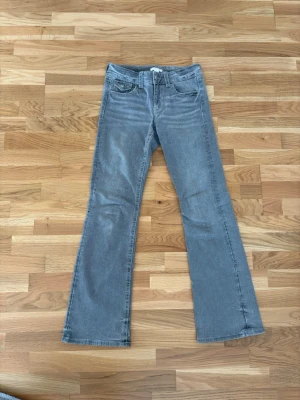 Grå bootcut jeans - Säljer ett par gråa bootcut jeans med klassisk femficksmodell och knappgylf. Jeansen har utsvängda ben och är tillverkade i ett mjukt denimtyg. Perfekta för dig som gillar en retroinspirerad look.