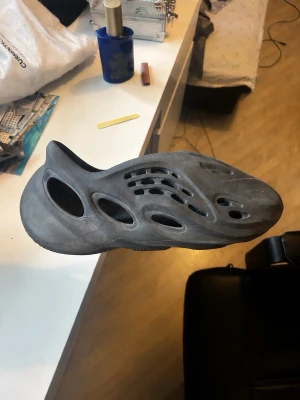 YZY foam runners  - Säljer ett par svarta foam rnrs med futuristisk design och flera hål för ventilation. Lätta och bekväma att bära, perfekta för chill dagar hemma eller ute. Unisexmodell med modern look.