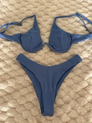 Blå ribbad bikini med bygel - Snygg blå bikini med ribbad struktur och bygel i toppen för extra stöd. Överdelen har smala axelband och triangelformade kupor.