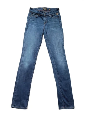 Blå raka jeans från Replay - Snygga blå jeans från Replay med raka ben och klassisk femficksdesign. Jeansen har en diskret tvättad look och detaljerade sömmar på bakfickan. Perfekta för dig som gillar en tidlös och avslappnad stil.