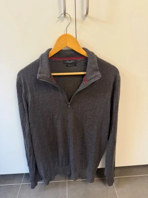 Luca Nobili half-zip i 100% extrafin merinoull, stl XL - Mörkgrå stickad tröja med halv dragkedja och hög krage. Tröjan har långa ärmar och ribbade muddar vid ärmslut och nederkant. Insidan av kragen har en diskret röd detalj. Perfekt för lager på lager och en clean look. NYPRIS 3000kr