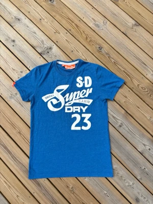 Superdry t shirt ~ Vintage  - Säljer denna Superdry t shirt i mycket bra skick och som är Vintage. Storlek M. Passar perfekt för dig som är mellan 175-180! Hör av er vid frågor eller minsta fundering 🙌  Längd: 69,5 cm  Bred: 47,5 cm  Ärm: 18,5 cm